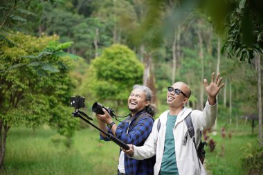 İki Endonezyalı erkek gezgin doğada yürürken video çekerken manzaranın fotoğraflarını çekiyorlar, seyahat konsepti.