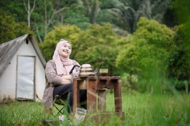 Endonezyalı genç kadın bir fincan sade kahvenin keyfini çıkarırken doğanın güzelliğinin ve rahatlatıcı atmosferinin tadını çıkarıyor. Seyahat kavramı..