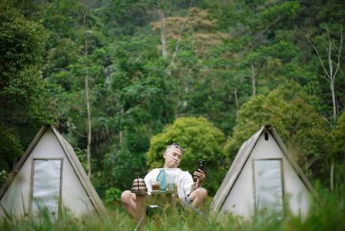Kel kafalı Endonezyalı bir adam, doğanın güzelliği ve atmosferinin tadını çıkarırken bir bardak sade kahvenin tadını çıkarıyor. Seyahat kavramı..