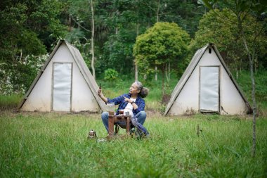 Bir orman kulübesinde kamp yaparken görüntülü konuşan kıvırcık saçlı Endonezyalı. Seyahat kavramı..