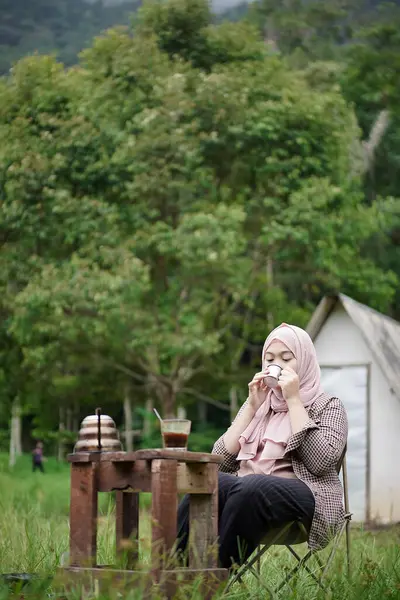 Endonezyalı genç kadın bir fincan sade kahvenin keyfini çıkarırken doğanın güzelliğinin ve rahatlatıcı atmosferinin tadını çıkarıyor. Seyahat kavramı..