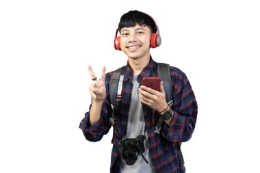 Genç heyecanlı Endonezyalı erkek sırt çantalı cep telefonu, seyahat konsepti kullanıyor, beyaz arka planda izole edilmiş..