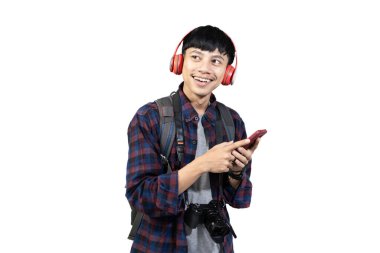 Genç heyecanlı Endonezyalı erkek sırt çantalı cep telefonu, seyahat konsepti kullanıyor, beyaz arka planda izole edilmiş..