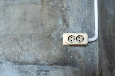 Group of white european electrical outlets with plug inserted into it on modern beige wall. Selective focus