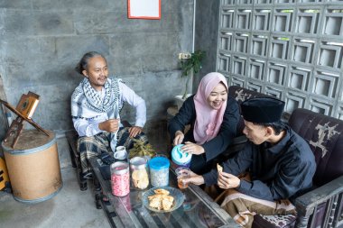 Evin arka verandasında otururken arkadaşça sohbet ediyoruz. Ramazan ayında köyde toplanan Müslüman ailelerin mutluluğu el sıkışıyor ve aile üyeleriyle bir araya geliyor.