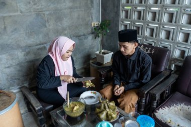 Lebaran 'da ketupat ve opor ayam yiyen genç bir çift. Lebaran konsepti. Müslüman bir aile. Lebaran mevsimi.