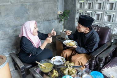 Lebaran 'da ketupat ve opor ayam yiyen genç bir çift. Lebaran konsepti. Müslüman bir aile. Lebaran mevsimi.