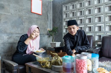 Lebaran 'da ketupat ve opor ayam yiyen genç bir çift. Lebaran konsepti. Müslüman bir aile. Lebaran mevsimi.