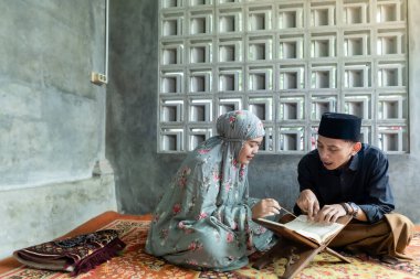 Asyalı Müslüman bir adam kadınlara Kuran ya da Kur 'an okumayı öğretiyor. Müslüman çift evde dua ediyor.