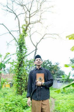 Endonezyalı gençler Müslüman kıyafetleri giyip Kuran 'a gidiyorlar. Kuran 'ı taşıyarak..