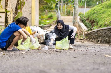 Çöp toplama. Bir grup Asyalı genç plastik atıkları ayırıyor. İnsanlar çöplerle uğraşırken görülüyor..