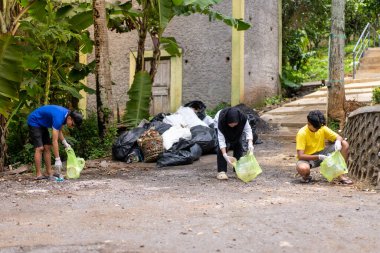 Çöp toplama. Bir grup Asyalı genç plastik atıkları ayırıyor. İnsanlar çöplerle uğraşırken görülüyor..