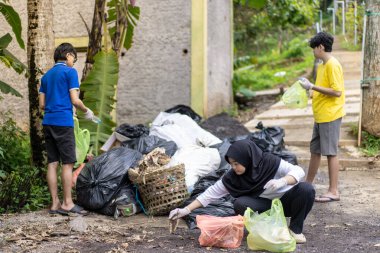 Çöp toplama. Bir grup Asyalı genç plastik atıkları ayırıyor. İnsanlar çöplerle uğraşırken görülüyor..