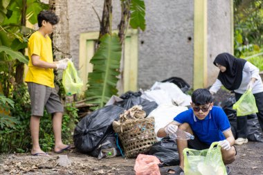 Çöp toplama. Bir grup Asyalı genç plastik atıkları ayırıyor. İnsanlar çöplerle uğraşırken görülüyor..