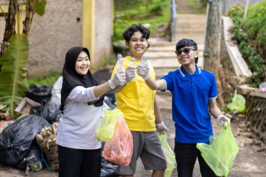 Çöp toplama. Bir grup Asyalı genç plastik atıkları ayırıyor. İnsanlar çöplerle uğraşırken görülüyor..