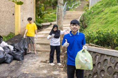 Çöp toplama. Bir grup Asyalı genç plastik atıkları ayırıyor. İnsanlar çöplerle uğraşırken görülüyor..
