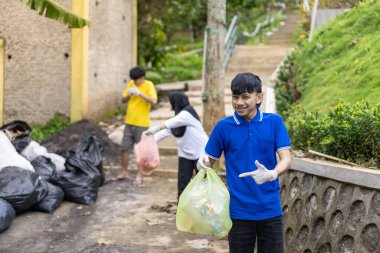 Çöp toplama. Bir grup Asyalı genç plastik atıkları ayırıyor. İnsanlar çöplerle uğraşırken görülüyor..