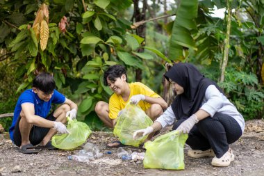 Çöp toplama. Bir grup Asyalı genç plastik atıkları ayırıyor. İnsanlar çöplerle uğraşırken görülüyor..