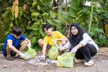 Çöp toplama. Bir grup Asyalı genç plastik atıkları ayırıyor. İnsanlar çöplerle uğraşırken görülüyor..