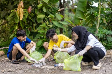 Çöp toplama. Bir grup Asyalı genç plastik atıkları ayırıyor. İnsanlar çöplerle uğraşırken görülüyor..
