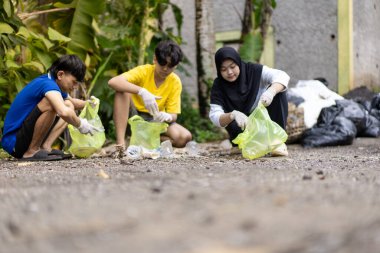 Çöp toplama. Bir grup Asyalı genç plastik atıkları ayırıyor. İnsanlar çöplerle uğraşırken görülüyor..