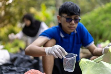 Çöp toplama. Bir grup Asyalı genç plastik atıkları ayırıyor. İnsanlar çöplerle uğraşırken görülüyor..