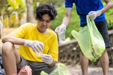 Çöp toplama. Bir grup Asyalı genç plastik atıkları ayırıyor. İnsanlar çöplerle uğraşırken görülüyor..