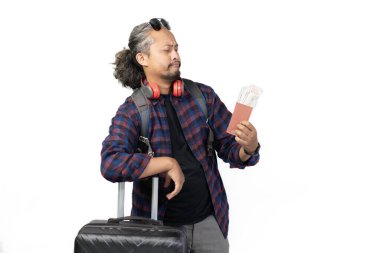 Kıvırcık saçlı Endonezyalı adam seyahat ederken para dolu valiz ve pasaport taşıyor, seyahat konsepti, beyaz arka planda izole edilmiş..