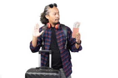 Kıvırcık saçlı Endonezyalı adam seyahat ederken para dolu valiz ve pasaport taşıyor, seyahat konsepti, beyaz arka planda izole edilmiş..