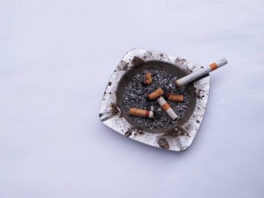 Kül tablası sigara izmaritleriyle doluydu ve çok kirli görünüyordu..