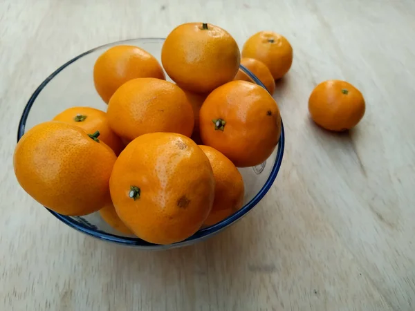 ボウルのオレンジは木製のテーブルで新鮮に見える — ストック写真