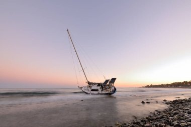Günbatımında Marbella 'da bir sahilde karaya vuran yelkenli.
