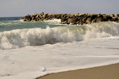 Rüzgardan gelen güçlü dalgalarla dalgalanan dalgalarda yüzen balıkçılar.