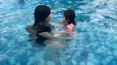 Genç anne ve güzel küçük kızı sabahları yüzme havuzunda yüzmeyi öğreniyorlar.