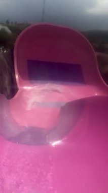 Yaz tatilinde yüzme havuzunda su kaydırağıyla su kaydırağı oynayan olgun bir Asyalı.