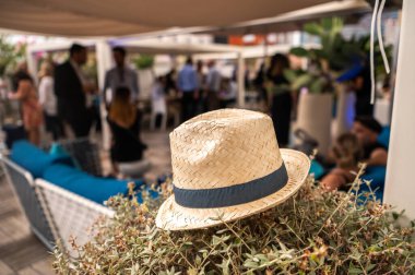 Arka planda kalabalık olan bir yaz partisinde rastgele yerleştirilen hasır şapka.