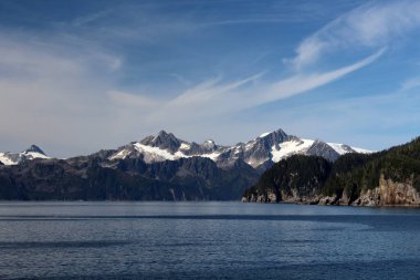 Alaska 'da Diriliş Körfezi' nin arka planında Kenai Fjords Ulusal Parkı 'nın sıradağları var.
