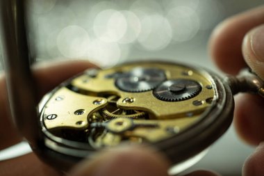 Saatçi atölyesindeki ahşap masa üzerinde eski yedek parça ve mekanik saatler yığını