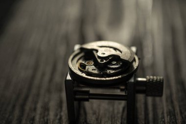 Saatçi atölyesindeki ahşap masa üzerinde eski yedek parça ve mekanik saatler yığını