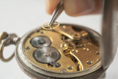 Profesyonel bir tamirci atölyede eski bir cep saati üzerinde çalışıyor..