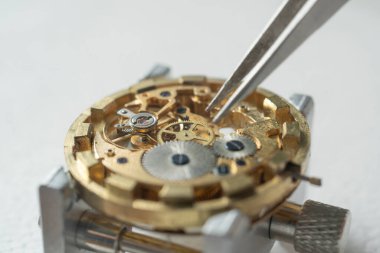 Profesyonel bir tamirci atölyede eski bir cep saati üzerinde çalışıyor..