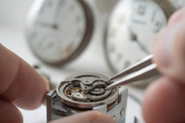 Profesyonel bir tamirci atölyede eski bir cep saati üzerinde çalışıyor..