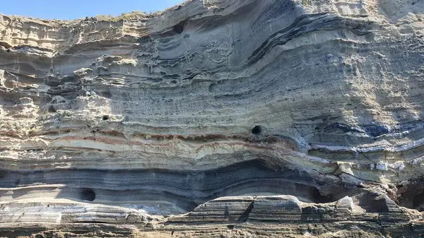 Ventotene (İtalya) adasının kayalıkları aşağıdan görülmektedir. Eski bir volkanın kalıntılarında renkli taş katmanları. Eylül 2023.