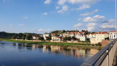 Elbe Nehri 'nin karşısındaki Meissen (Almanya) evlerinin manzarası. Sakin bir yaz akşamıydı. Güneş sudan yansıyordu. Mavi gökyüzünde kabarık bulutlar.