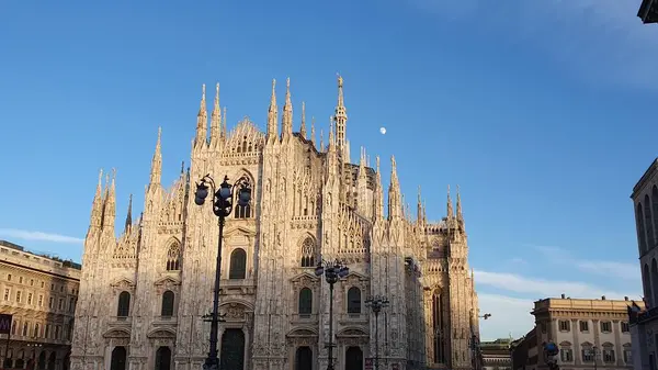İtalya, Milano 'daki Duomo Katedrali' ne karşı mavi bir kış göğü. Öğleden sonra dolunay görülebilir. Aralık 2023.