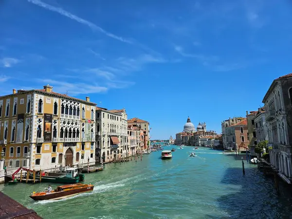 Venedik (Venezuela), İtalya, Mayıs 2024. Santa Maria della Salute Bazilikası 'na doğru Büyük Kanal manzarası. Tahta kayıklar ve gemiler berrak mavi gökyüzüne karşı derin turkuaz sularda yüzüyorlar..