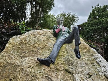 Dublin, İrlanda 'da Oscar Wilde Anıt Heykeli (Temmuz 2024). Yazarın rengarenk heykeli bir kayanın üzerinde kayıtsızca yatıyor.. 