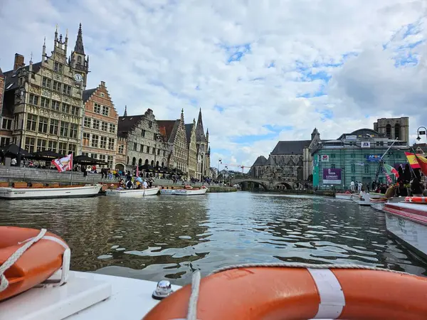 Gent, Belçika (Mayıs 2024). Şehir merkezindeki bir kanalın su yüzeyi, bir tekneden görülüyor. Ön planda turuncu yaşam şamandırası, kıyıda duran eski Flaman evleri.