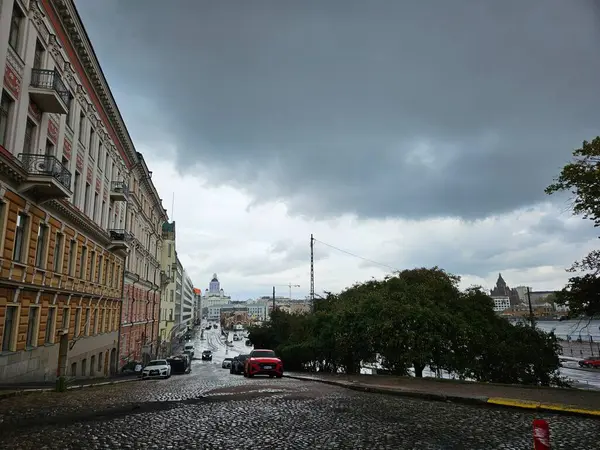 Helsinki, Finlandiya (Eylül 2024). Cobblestone Caddesi, kara yağmur bulutlarının altında. Ufuktaki Helsinki Katedrali.