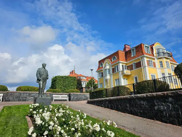 Helsinki, Finlandiya (Eylül 2024). Yazar Juhani Aho 'nun heykeli (1861 - 1921) yazarın adı verilen bir parkta, yazarın evi olan sarı malikanenin önünde.. 